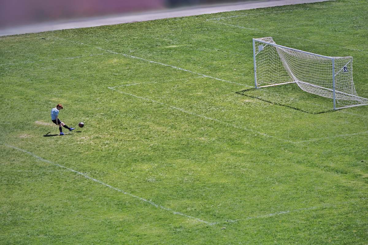 team sport person kicking ball near white goalpost people